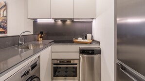 Cocina compacta equipada con lavavajillas, horno y refrigerador de acero inoxidable.