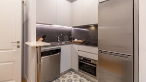 A compact kitchen with a built-in dishwasher, oven, and a stainless steel refrigerator. - Elegant Apartment in Las Letras (Madrid)