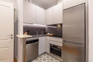 A compact kitchen with a built-in dishwasher, oven, and a stainless steel refrigerator. - Elegant Apartment in Las Letras (Madrid)