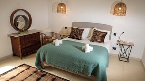 Ein Schlafzimmer mit einem Bett, einem Schminktisch, einem Spiegel, zwei Nachttischen und zwei Pendelleuchten.