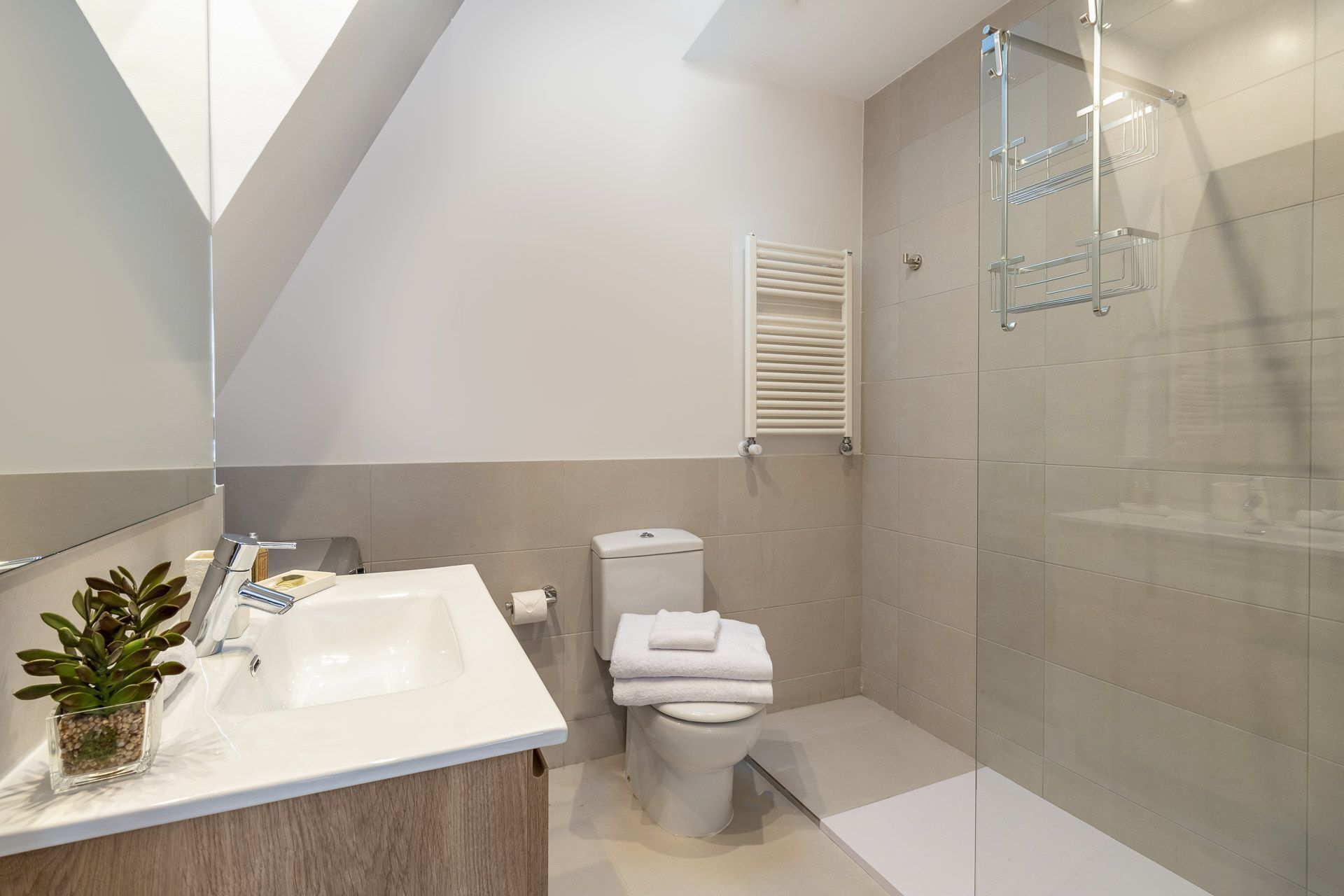 Een moderne badkamer met een wit wastafel, toilet en douche.