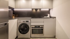 Een kleine keuken met een ingebouwde wasmachine en oven, roestvrijstalen apparatuur en een modern design.
