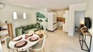 A modern apartment with a dining area, a living room with a green sofa, a kitchen, and a TV on a stand. - Bright House - AC - 2br-4p - Gassin (Gassin)