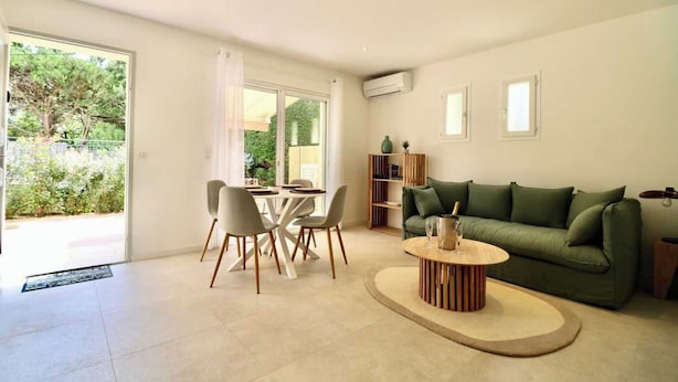 A modern living room with a green sofa, a dining table with chairs, and a coffee table. There is a sliding glass door leading to a garden. - Bright House - AC - 2br-4p - Gassin (Gassin)