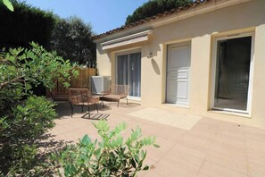 A building with a patio area, wicker furniture, and a sliding glass door. - Bright House - AC - 2br-4p - Gassin (Gassin)