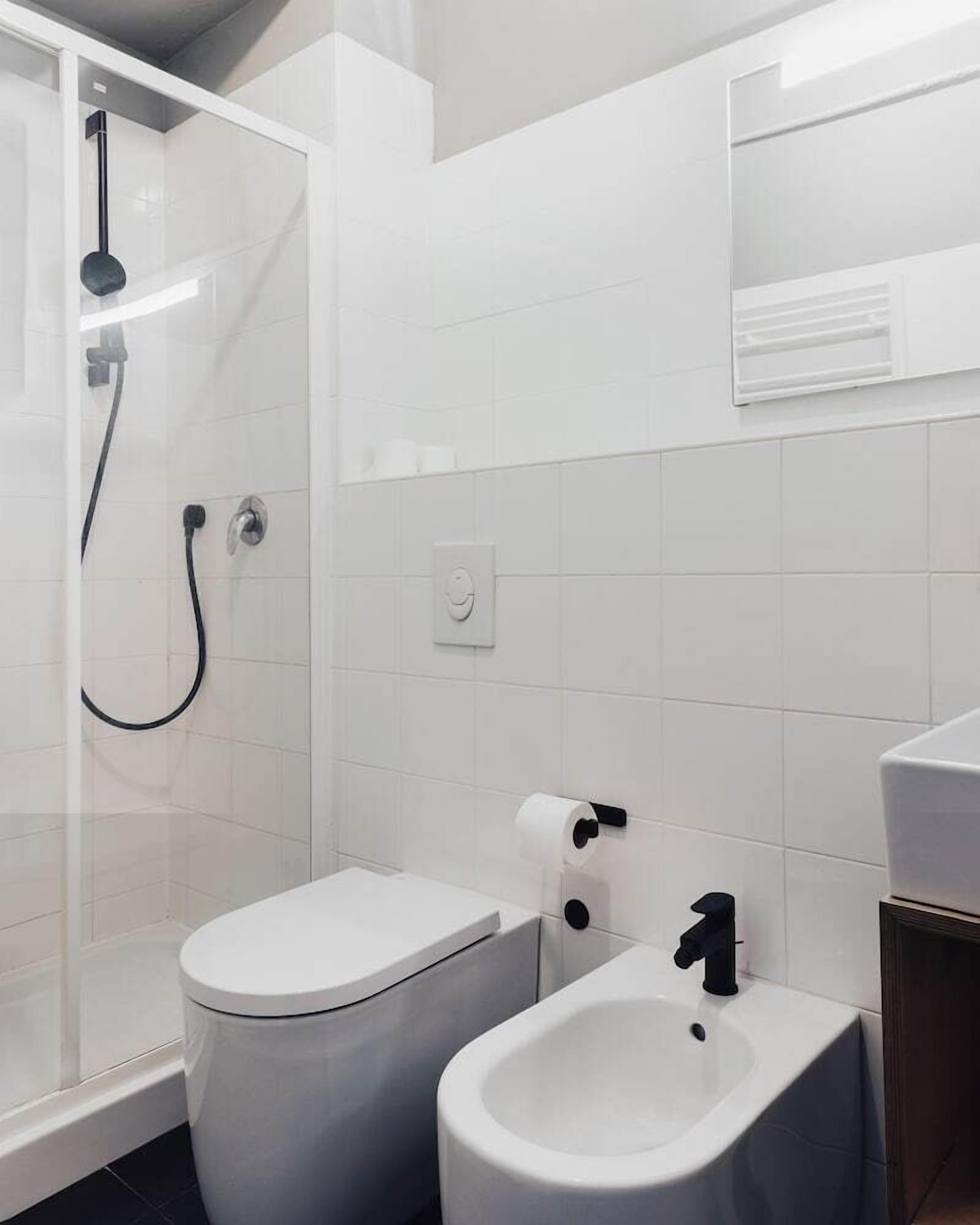 A modern bathroom with a shower, toilet, bidet, and sink.