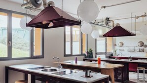 Une cuisine moderne dotée d’un îlot central, d’appareils électroménagers en acier inoxydable et de luminaires suspendus.