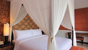 Una habitación de hotel con una cama con dosel, un cabecero estampado, una lámpara de noche y un banco.