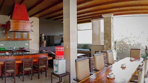 Una cocina moderna con armarios de madera, una lámpara colgante roja y un comedor con una mesa larga y sillas.