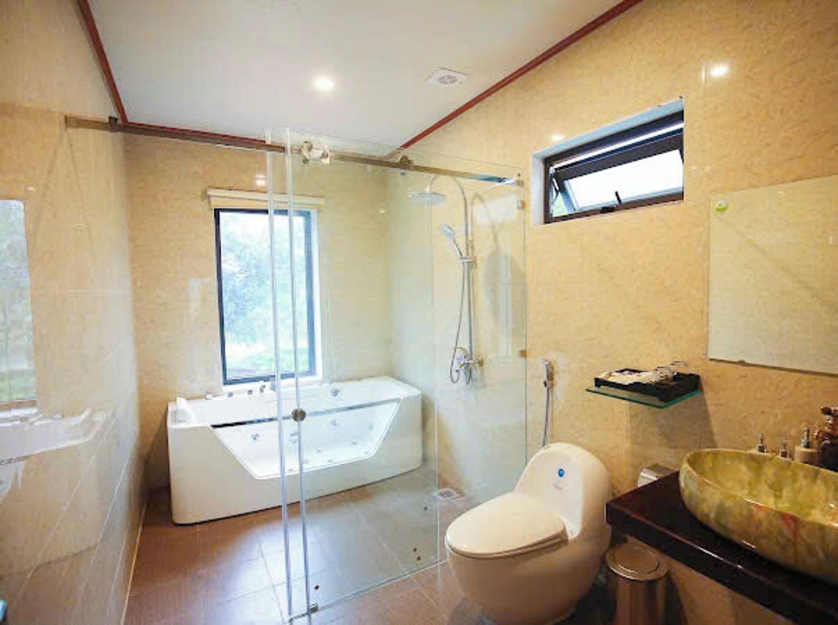 A bathroom with a glass-enclosed shower, a bathtub, a toilet, and a vanity with a large sink.