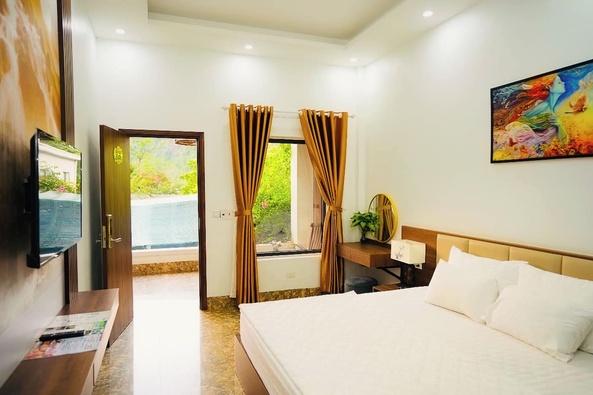 Una camera d'albergo con un letto, una scrivania con una lampada, una televisione e un quadro appeso al muro.