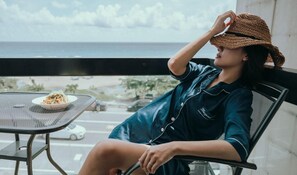 A person seated at a table with a plate of food, overlooking a view of the ocean and a road. - Sasa Nor Lamour B B (Hengchun)