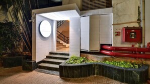Une entrée moderne avec une fenêtre circulaire, un escalier et une boîte rouge pour le matériel de sécurité incendie.