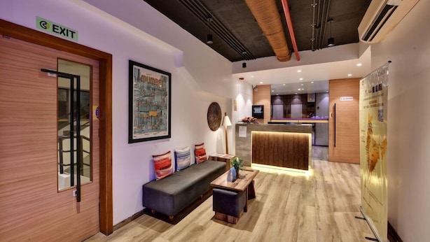 Un hall d’entrée moderne comprenant un comptoir d’accueil, un espace détente avec un canapé et une table basse, ainsi qu’un panneau indiquant la sortie.