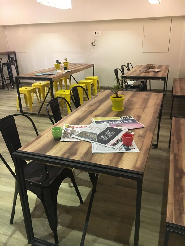 A conference room with wooden tables and yellow chairs, some with potted plants. - Istay Hotels Andheri Midc (Mumbai)