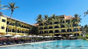A hotel with a pool area, multiple floors, and palm trees. - Hon Rom 1 Resort (Phan Thiet)