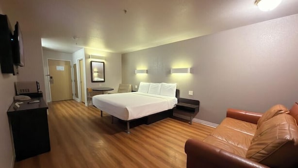 Ein Hotelzimmer mit Bett, Schreibtisch, Sessel, Sofa und Fernseher.