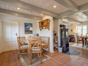 A cozy kitchen with a wooden table, chairs, a stove, and a painting on the wall.