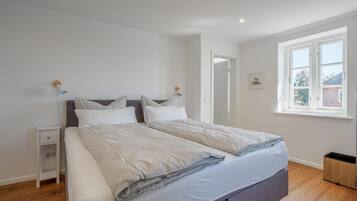 A bedroom with a bed, bedside tables, a window, and a door.