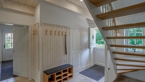 A modern interior with a wooden staircase, a bench, and a wall-mounted coat rack. - 5-Star Thatched Holiday Home "Emmas Hus" with Sauna and Fireplace (Pellworm)