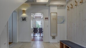 A spacious hallway with a dining area, wooden beams, and a bench. - 5-Star Thatched Holiday Home "Emmas Hus" with Sauna and Fireplace (Pellworm)