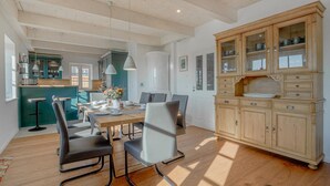 A spacious dining area with a wooden table, modern chairs, and a large cabinet with glass doors. - 5-Star Thatched Holiday Home "Emmas Hus" with Sauna and Fireplace (Pellworm)