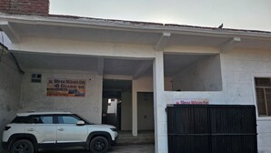 Ein weißer SUV vor einem Gebäude mit der Aufschrift Shree Nilyam Inn.