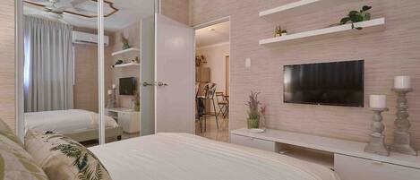 A modern bedroom with a large bed, a TV mounted on the wall, and a sliding door leading to a bathroom.
