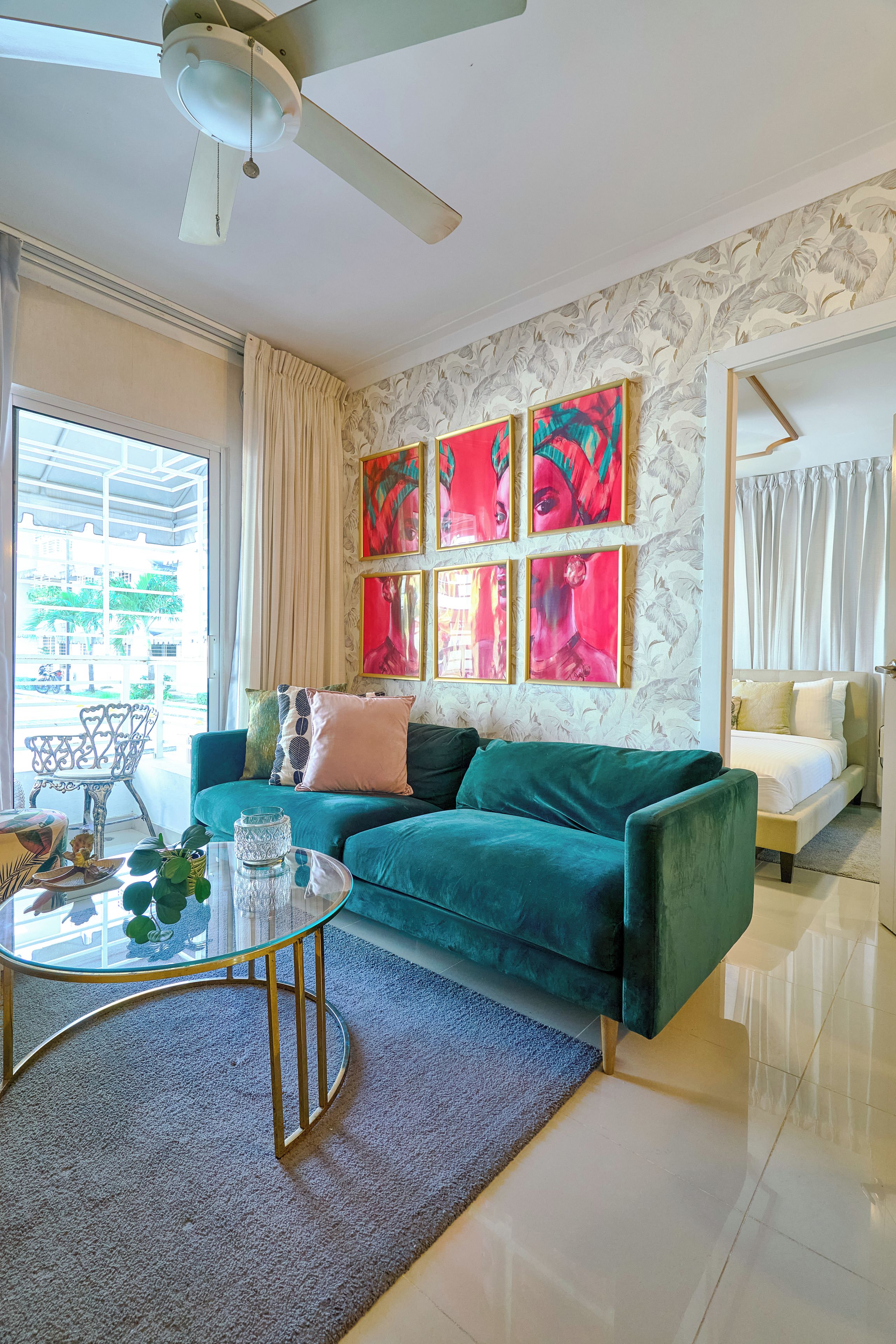 A modern living room with a teal sofa, a glass coffee table, and a ceiling fan.