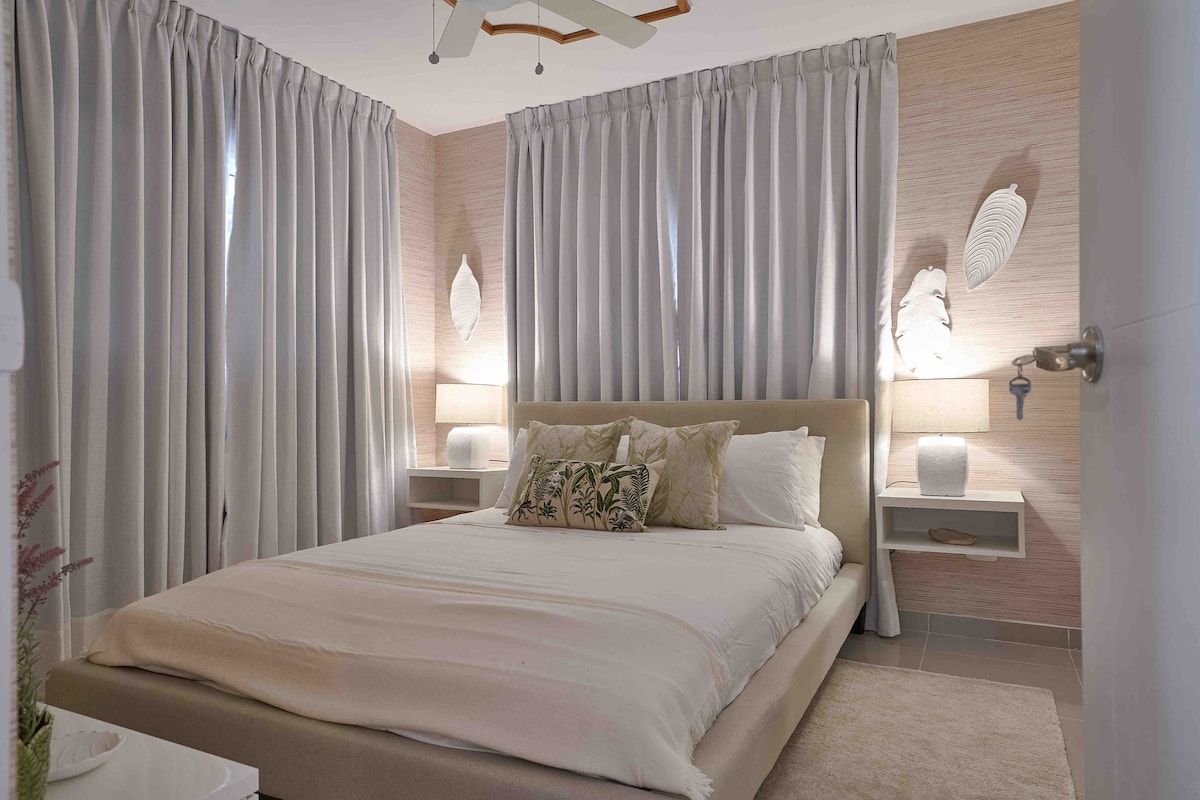 A modern bedroom with a large bed, two bedside tables with lamps, and a wooden accent wall.