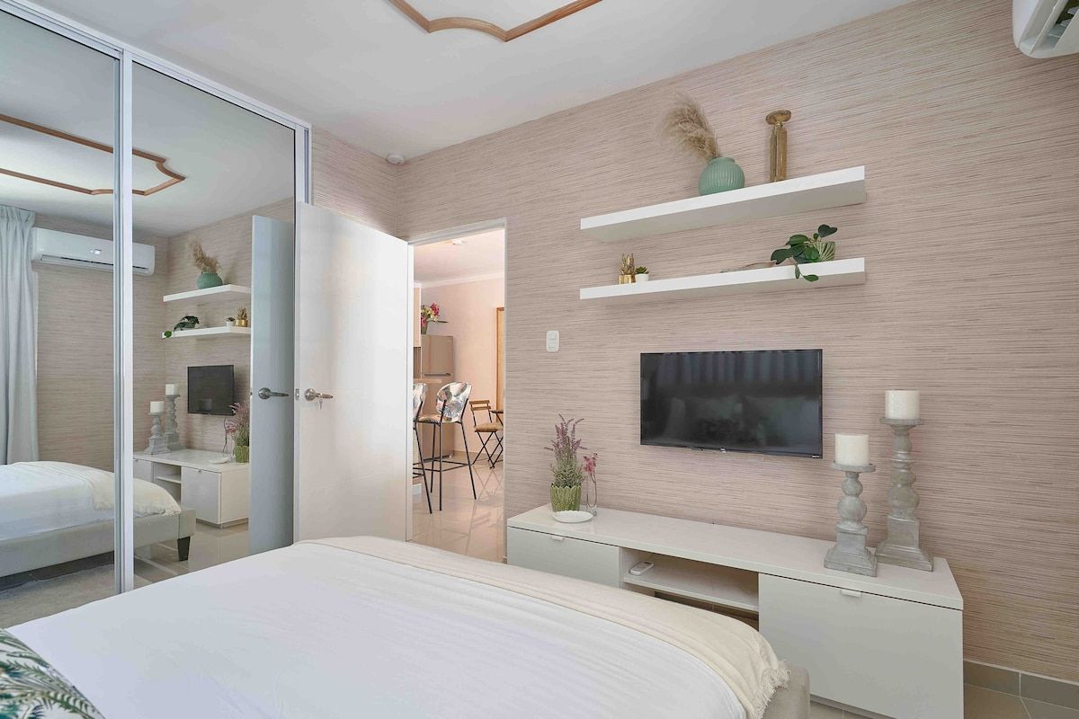 A modern bedroom with a large bed, a TV, and a desk.
