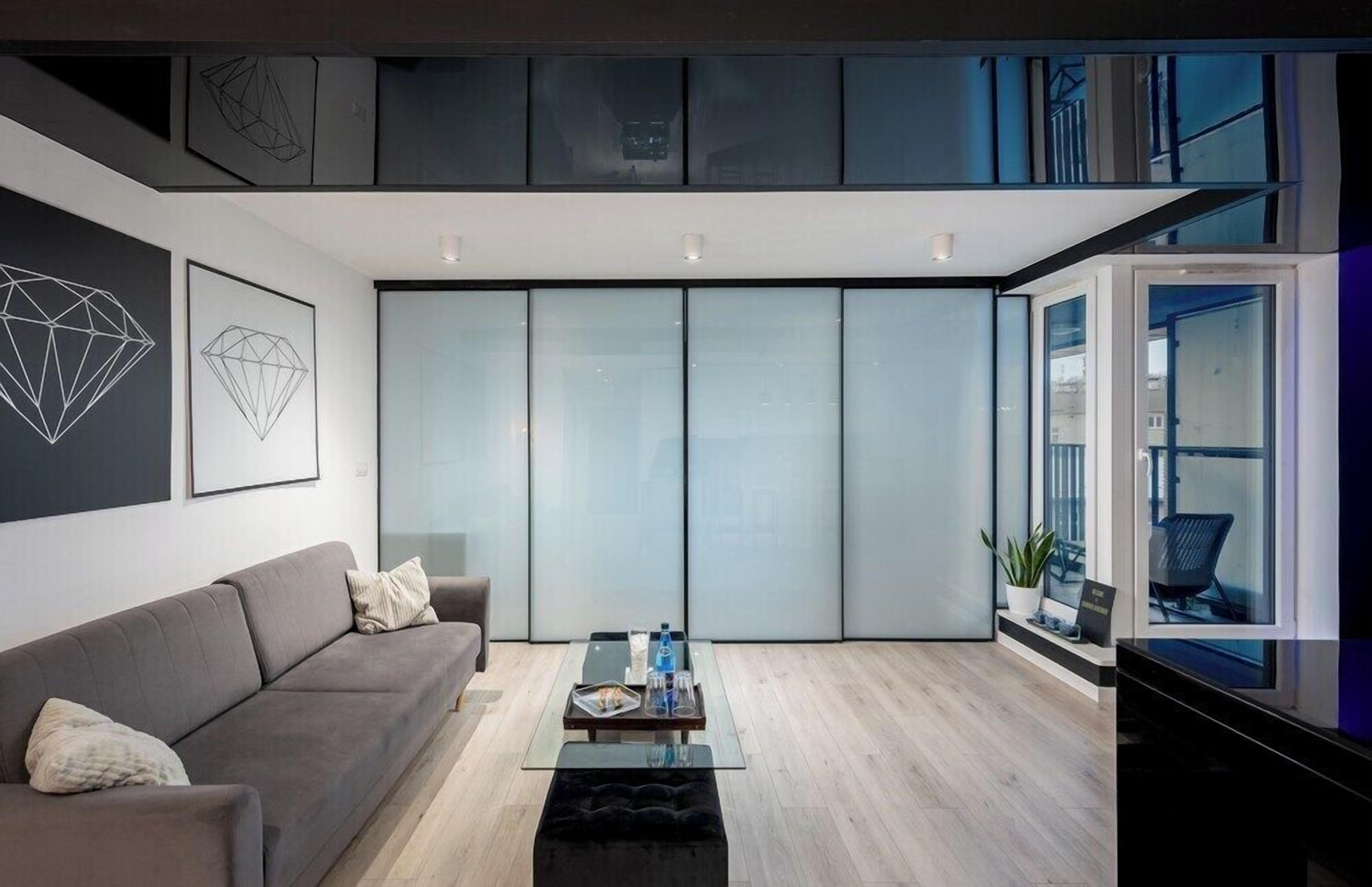 Una sala de estar moderna con un sofá, una mesa de centro y un muro divisorio de vidrio.