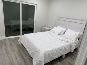 A bedroom with a bed, a nightstand, and a sliding glass door leading to another room. - Luxurious house on the lake for 10 ppl. (Orlando)