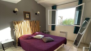 Quarto com cama, escrivaninha, janela com cortinas e radiador.