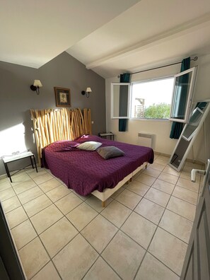 A bedroom with a bed, a desk, a window with curtains, and a radiator. - Villa Lume di Corsica in Porto-Vecchio, air-conditioned, swimming pool, near Palombaggia (Porto-Vecchio)