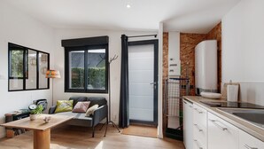 A modern kitchen with a dining area, a sofa, and a large window. - Chalet at the Gates of Goulet (Plouzané)