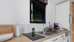 A modern kitchen with a wooden countertop, a built-in washing machine, and a window with blinds. - Chalet at the Gates of Goulet (Plouzané)