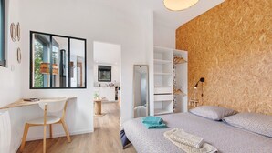 A modern bedroom with a wooden floor, a bed with patterned bedding, a desk with a chair, and a large mirror. - Chalet at the Gates of Goulet (Plouzané)