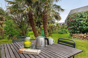 Een houten tafel met een waterkoker, mok en een bakje brood.