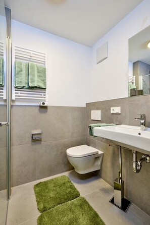 A modern bathroom with a toilet, sink, and shower. - Deluxe Single with Kitchenette (Starnberg)