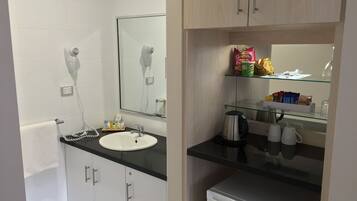A modern bathroom with a sink, mirror, towel rack, and a small refrigerator.