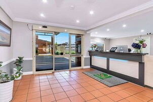Zona de recepción con mostrador, puerta de cristal y piso de baldosas.