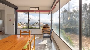 A modern room with a wooden table, chairs, a large window, and a view of buildings and trees.