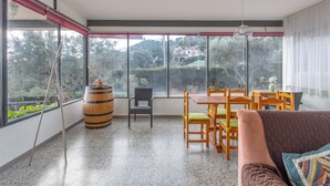 A spacious room with large windows, a wooden dining table, and a cozy seating area.