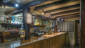 Un coin bar avec des poutres en bois, une variété de bouteilles et un panneau accroché au mur.