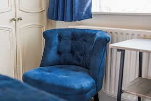 A room with a blue upholstered chair, a white radiator, and a white cabinet with doors. - 4 BR | Downstairs Bedroom Streatham | Sleeps 8 (London)