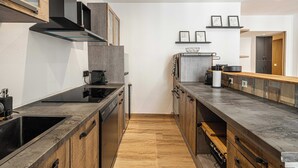 A modern kitchen with dark countertops, wooden cabinets, and a central island. There are framed pictures on the wall and a built-in oven. - Magnificent Apartment - AC- 2br- 4P - Cannes (Cannes)