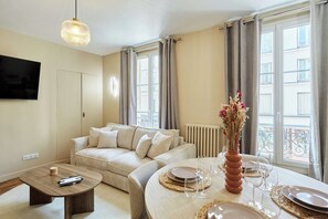 Una sala moderna con sofá, mesa de centro y comedor para cuatro.
