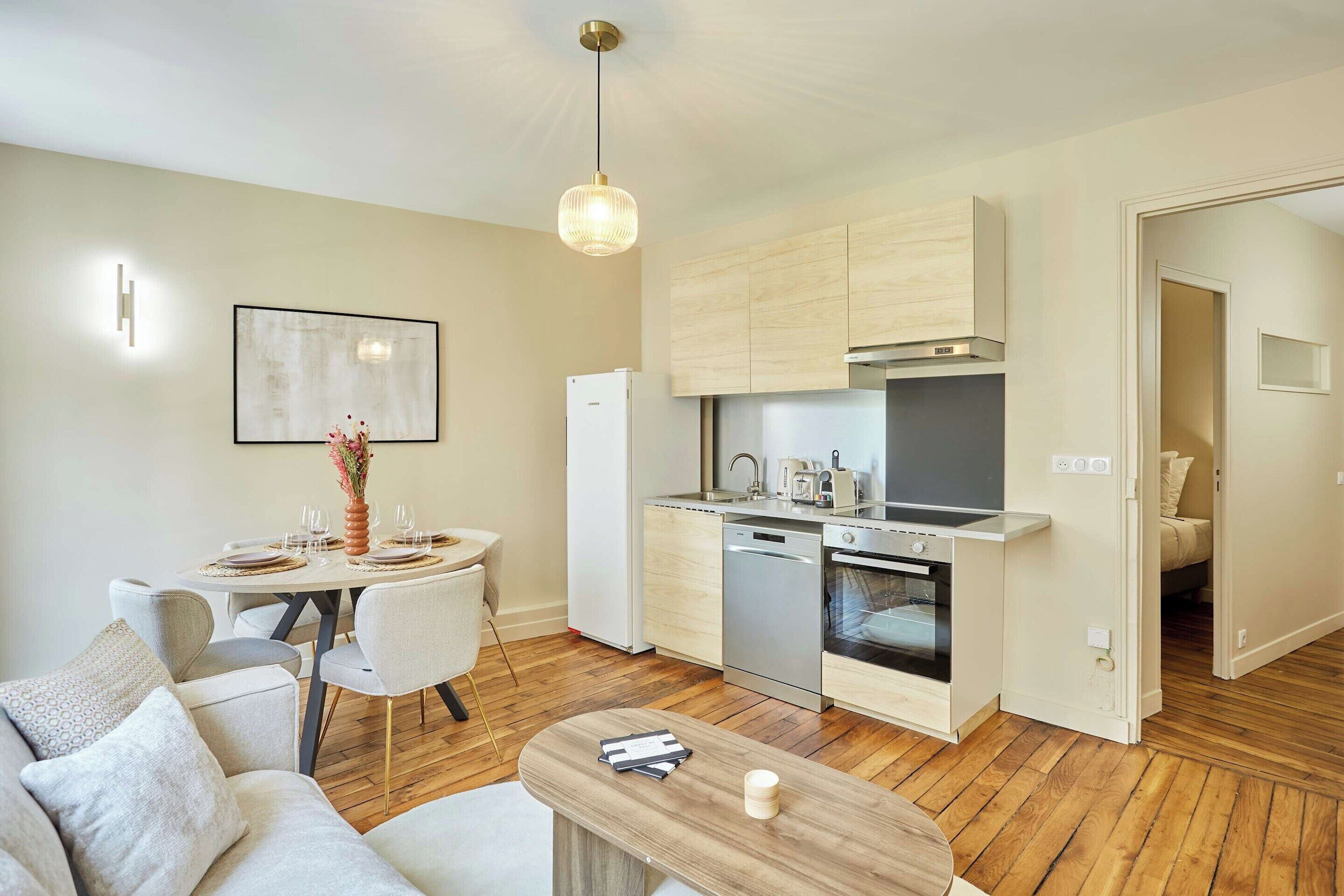 A modern kitchen with a dishwasher, oven, and a dining area with a table set for two.