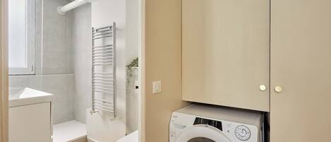 A compact bathroom with a washing machine, a shower, and a toilet.